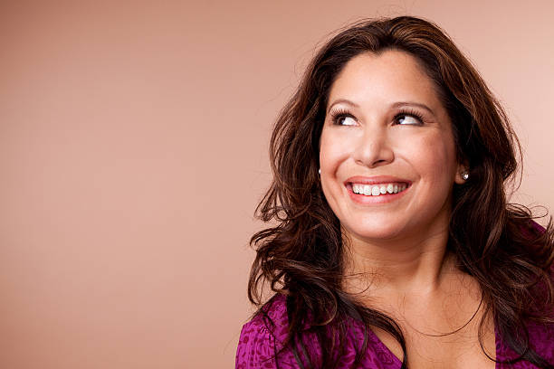 Headshot of a brunette haired mid aged woman cheerful smiling and looking at camera.