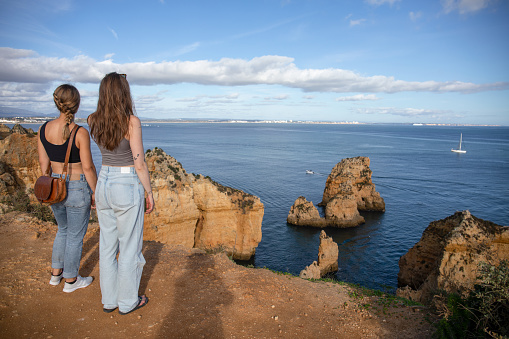 Young women relax on cliff over the Atlantic Ocean, in the Algarve