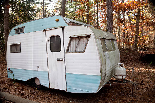 Abandoned Retro Travel Trailer, Mobile Home Old camper trailer rotting in the woods in a junkyard. Autumn color. terryfic3d stock pictures, royalty-free photos & images
