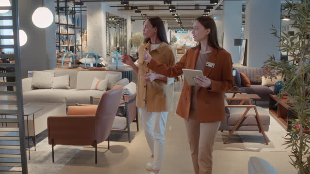 Saleswoman and Customer Walking around Furniture Store