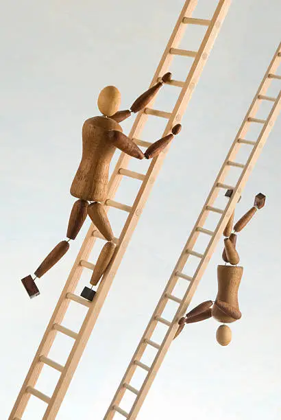 Two wooden figures climb ladders in opposite directions.These are unique and original wooden figures with accessories crafted by the photographer from recycled materials.  All the items in this image are carefully hand crafted and owned by the photographer.