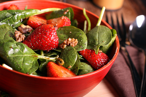 Fresh spinach and pecan salad in red wood bowl