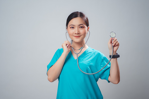 Asian woman wearing doctor uniform doctor happy smiling holding stethoscope standing isolated over white background.