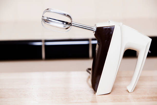 Old-Fashioned Mixer Old-fashioned kitchen mixer with silver beaters resting on a wood table. electric whisk stock pictures, royalty-free photos & images