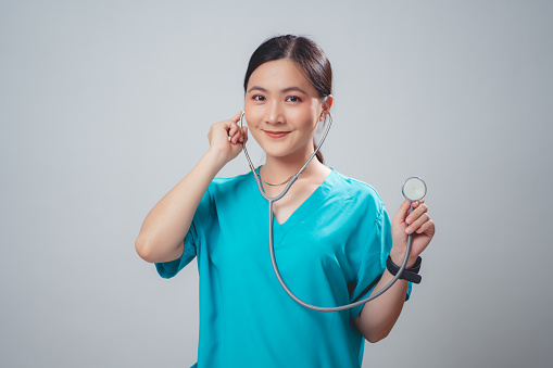 Asian woman wearing doctor uniform doctor happy smiling holding stethoscope standing isolated over white background.