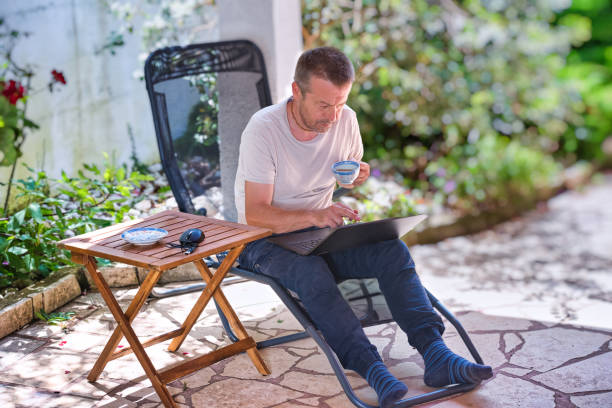 istock Man Relaxing on Terrace, Drinking Coffee and Using Laptop 1822270357