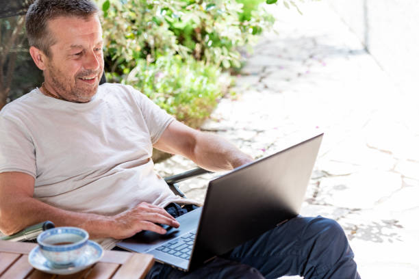 istock Man Relaxing on Terrace, Drinking Coffee and Using Laptop 1822270364