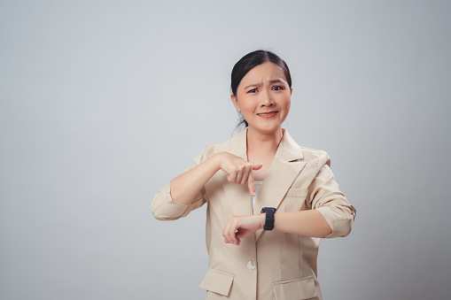 Asian woman anxiety with wrist watch standing isolated over white background.