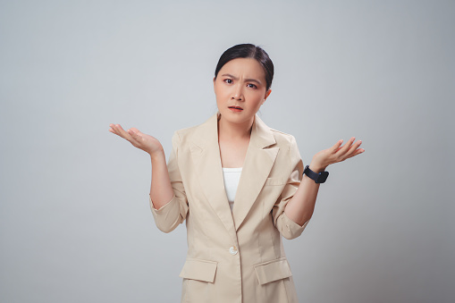 Asian woman angry annoyed and shrugging shoulders standing isolated over white background.