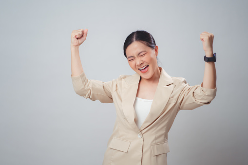Asian woman happy smiling showing a winning gesture standing isolated on white background.