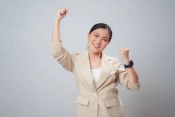 Photo of Asian woman happy confident make a winning gesture standing isolated on white background.