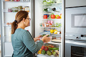 Woman takes containers with raw food from fridge