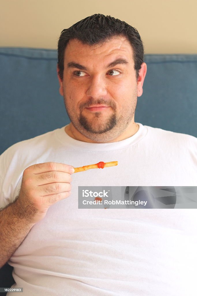 Man spills ketchup on t-shirt A large man spills ketchup on his t-shirt and looks around to see if anyone noticed.  Not a good day to wear a white t-shirt and eat french fries! Spilling Stock Photo