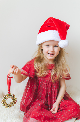 Little Beautiful Girl in Santa Hat Red Party Dress Waiting for Christmas and New Year Indoor Happy