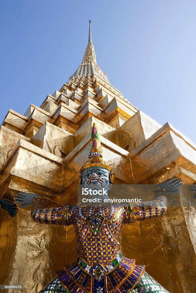Mythical figure and golden chedi, Grand Palace, Bangkok. Statue of a mythical figure holding up a golden chedi, Grand Palace, Bangkok.  Architecture Stock Photo