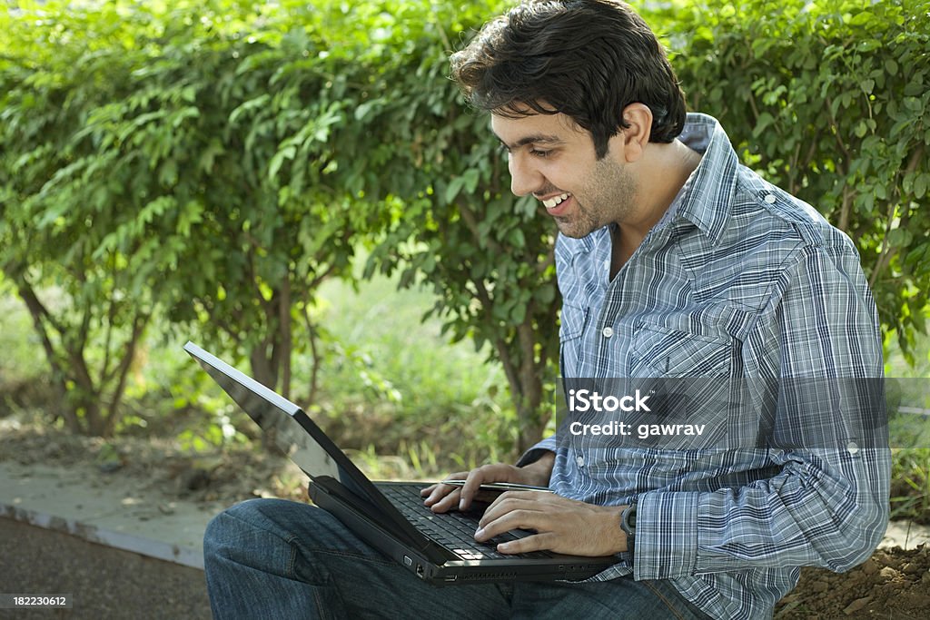 Feliz joven está trabajando en una computadora portátil en el día. - Foto de stock de 25-29 años libre de derechos