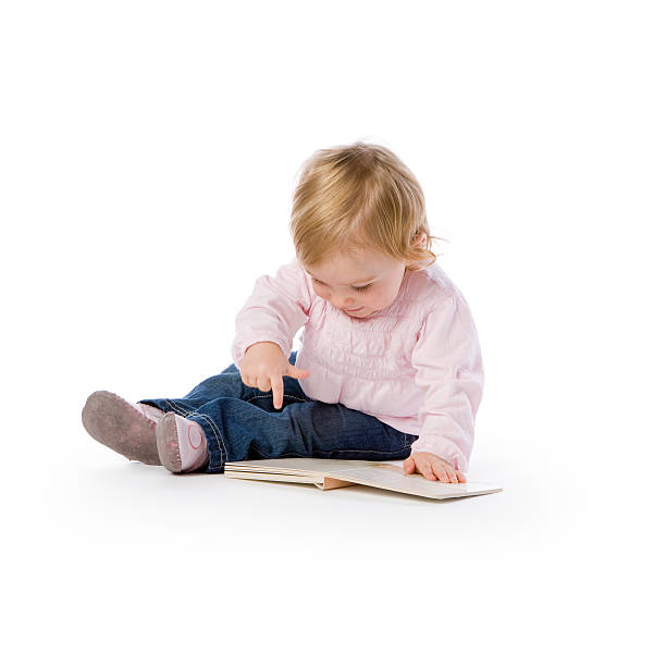 Cute little child play with book and wearing glasses while sitting on floor isolated over white background, Asian baby boy and education concept
