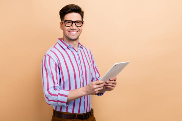 istock Portrait of cheerful guy business assistant using wireless tablet searching information in internet isolated on beige color background 1822316612