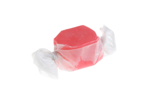 Single isolated piece of strawberry salt water taffy on white backgroundHorizontal composition