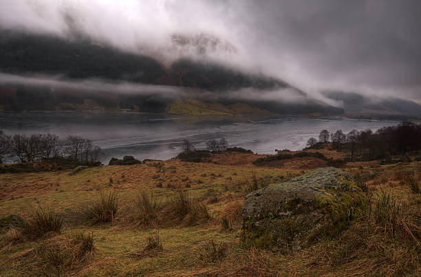 Winter in The Trossachs, Scotland. "The ice melts on Loch Voil, in the Trossachs of Scotland on a typical damp, cold, winters day.  Low cloud covers the hills and raindrops cling to the grass." loch voil stock pictures, royalty-free photos & images