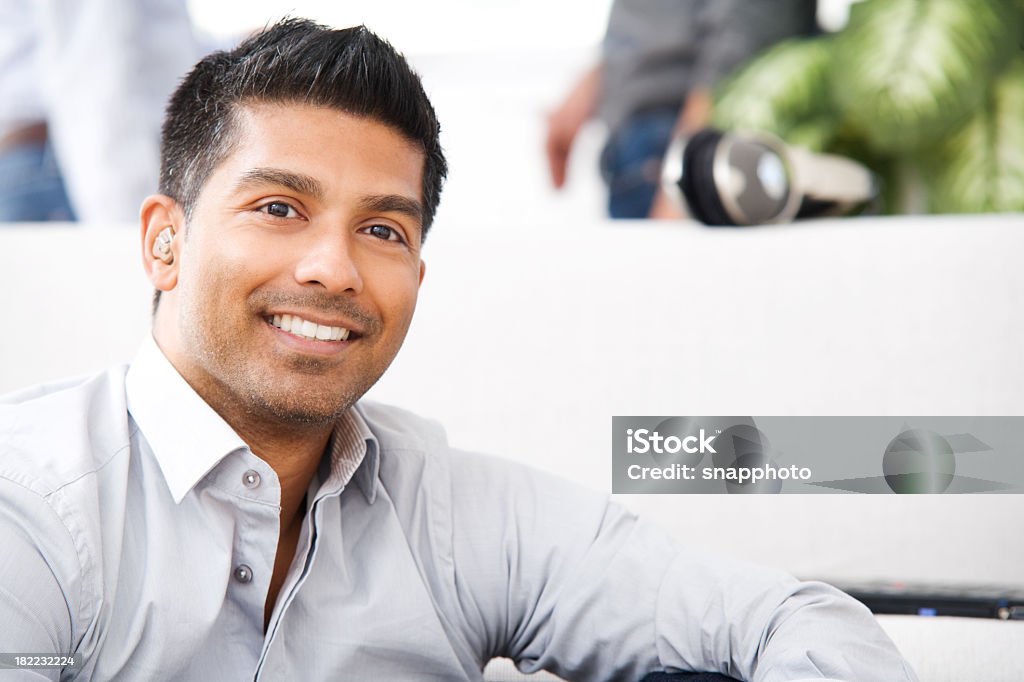 An attractive man is smiling while relaxing at home - 免版稅助聽器圖庫照片