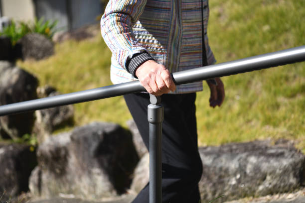 Senior woman climbing the slope Senior woman climbing up a slope holding a handrail slow walk stock pictures, royalty-free photos & images