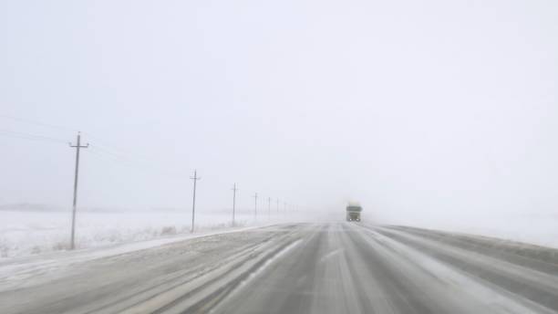 istock Dangerous road with ice and blizzard, clearing windshield, view from car as truck approaches. Hazardous journey on treacherous road, emphasizing risks. Confronting dangers on icy road, safety first. 1822329541