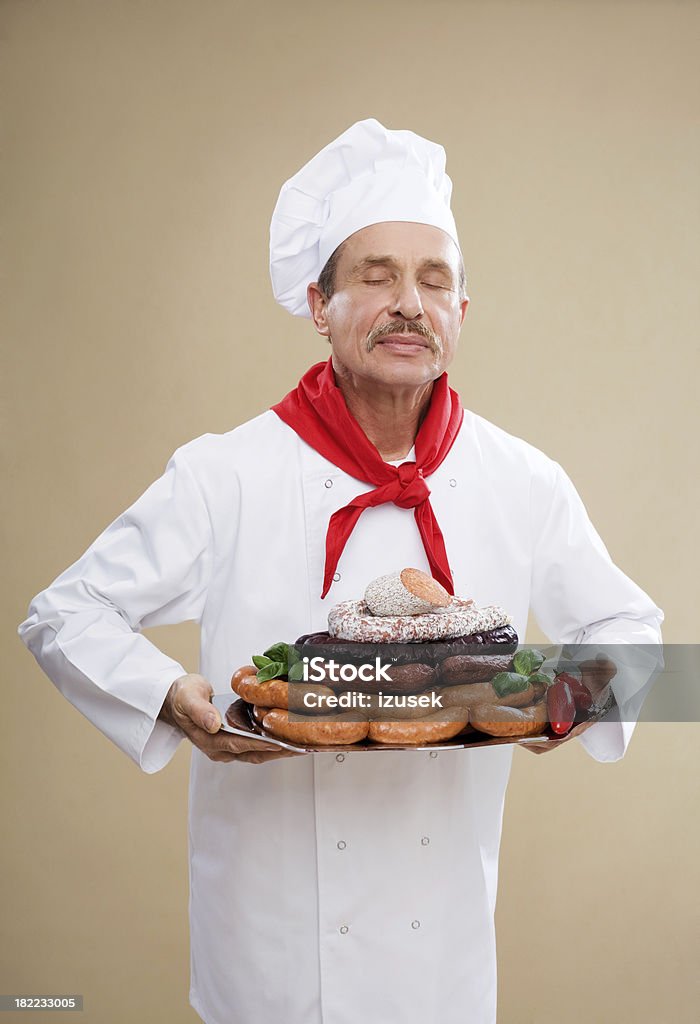 Macellaio con varietà di salsicce - Foto stock royalty-free di Abito da cuoco