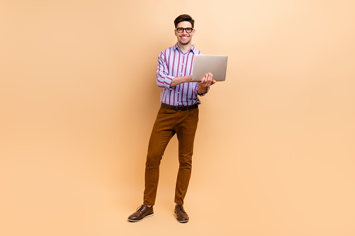 Full length photo of attractive man it specialist wear stylish clothes hold modern netbook macbook isolated on beige color background