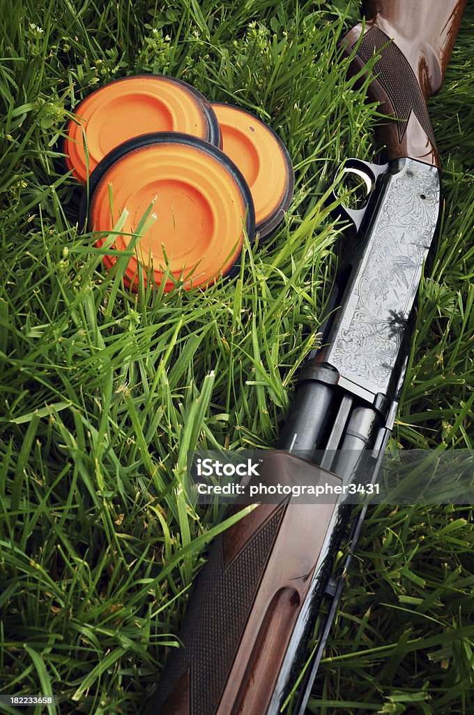 Shotgun and Clay Pigeons Shotgun sitting in the grass next to three clay pigeon targets. Shooting a Weapon Stock Photo