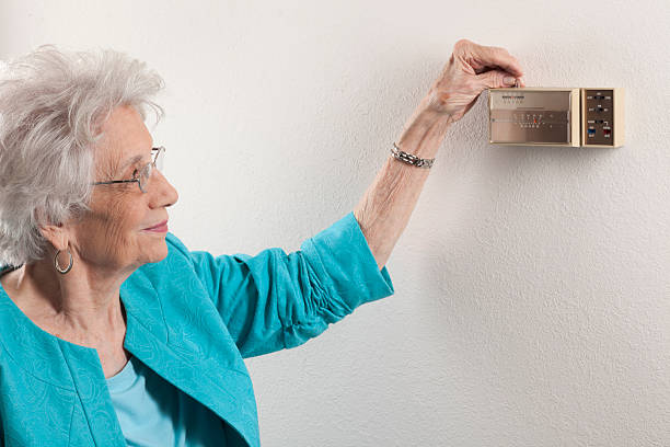 istock senior woman adjusting home thermostat 182233890