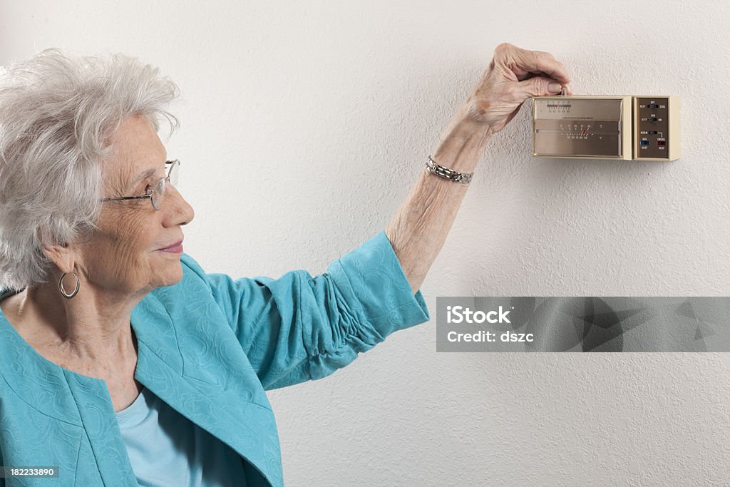 Sênior mulher, ajustando casa o termostato - Foto de stock de Bomba de calor royalty-free
