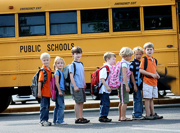 istock Elementary age kids in front of school bus. 182234401