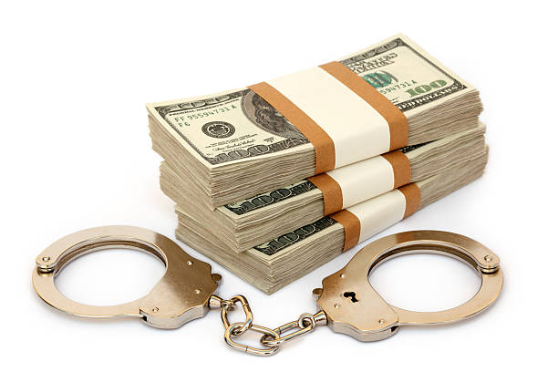 Handcuff and money Business fraud concept with handcuff and us dollars. white collar crime handcuffs stock pictures, royalty-free photos & images