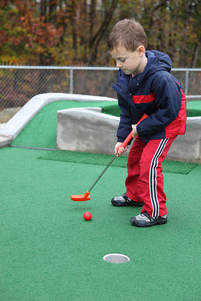 istock Little boy with determined look putting at mini golf 182235566