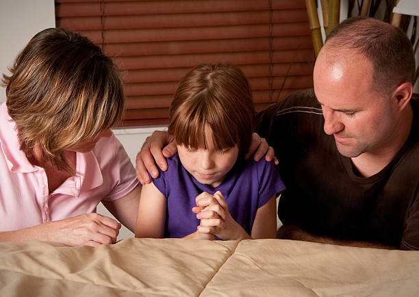 Girl praying with her mom and dad