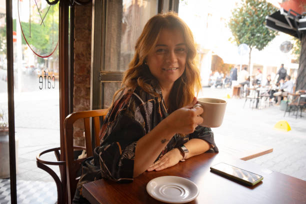 istock Happy young woman using mobile phone and enjoying coffee at cafe 1822359984