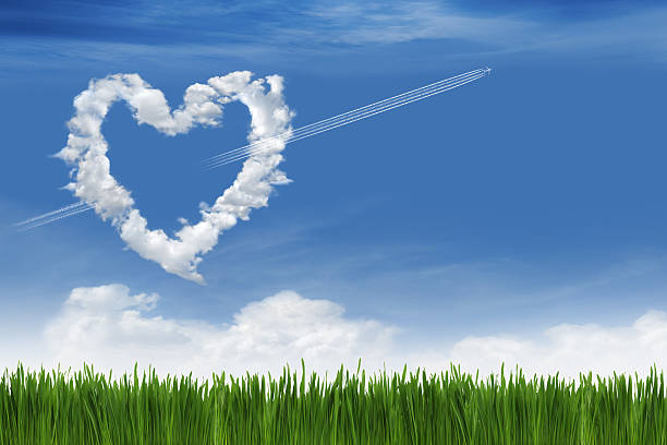 Love In The Sky Grass area with clouds in the shape of heart and airplane's contrail like a Cupid's arrow. words in the sky stock pictures, royalty-free photos & images