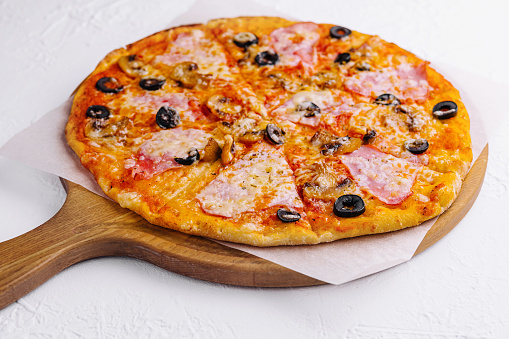 pizza with ham and mushrooms on a light background