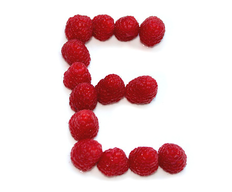 letter E made from raspberries. isolated on white background for birthday party, cards, anniversary, celebration, cookery books, vegan dessert, voucher or coupons, present vouchers, gift coupon