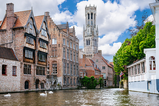 Gent, Flanders, Belgium -  June 21, 2019: Shot from castle tower, view over city roofs shows six most important and historic towers of Belfry, churches, Postal service, and university. Fish market gate. Cloudscape with blue patches.