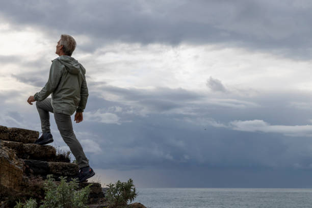 Mature man climbs steps above sea