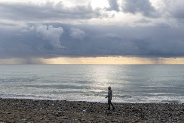 istock Man walks along empty beach on stormy day 1822408072