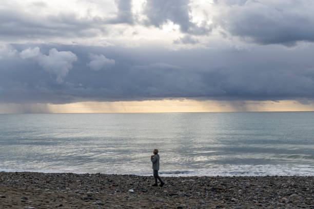 istock Man walks along empty beach on stormy day 1822408075