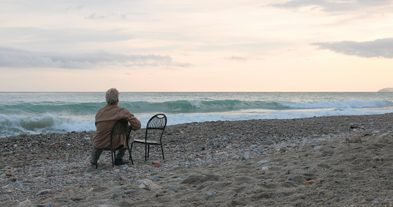 Senior man relaxes on beach chair at sunrise