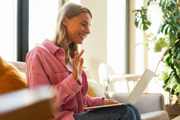istock Smiling young female freelancer using laptop, having video call, using laptop, waving hand 1822412380