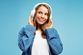 Portrait of attractive young woman wearing casual clothes listening to music in wireless headphones