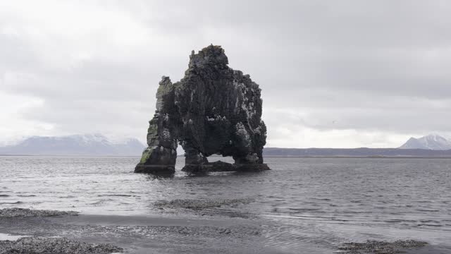View from black sand beach over Hvitserkur rock formation during overcast day