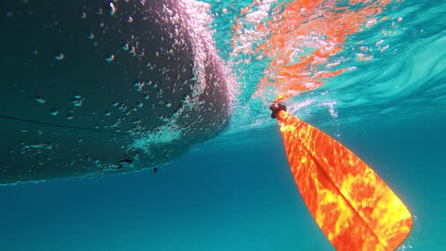 Underwater view of kayak and paddle on transparent turquoise water