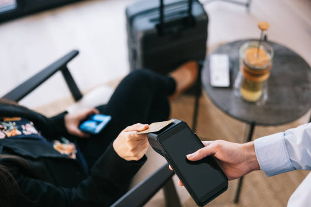Businesswoman paying with credit card at airport business lounge Businesswoman pays for her tea using contactless payment in the airport VIP lounge contactless airport stock pictures, royalty-free photos & images
